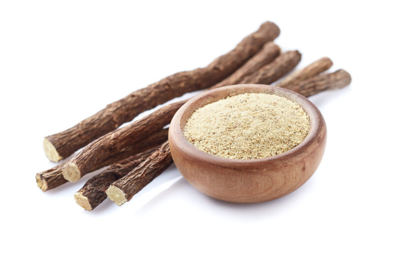 Licorice powder with dry roots on white background